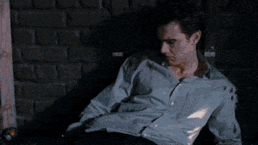 a man in a blue shirt is laying down with a picture of a man in a suit next to him