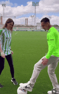 a man in a green shirt with the word volvo on the front is kicking a soccer ball