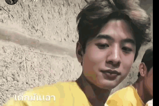 a young man wearing a yellow shirt is looking at the camera and smiling .