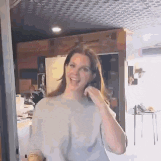 a woman is smiling while standing in a room in front of a door .