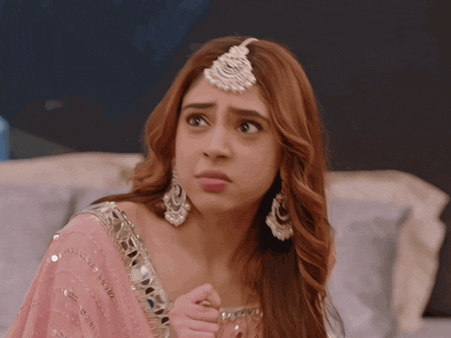 a woman wearing a pink dress and earrings is making a face