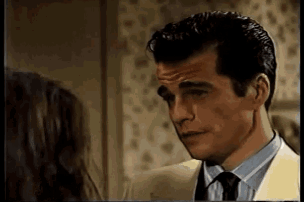 a man in a suit and tie is standing next to a woman in a room .