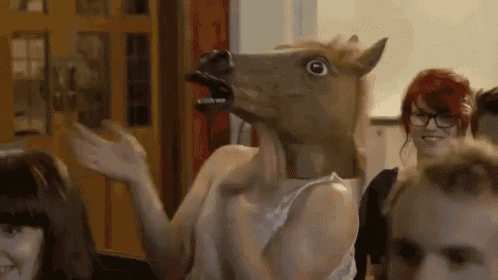 a woman wearing a horse head mask is dancing in a room with other people .