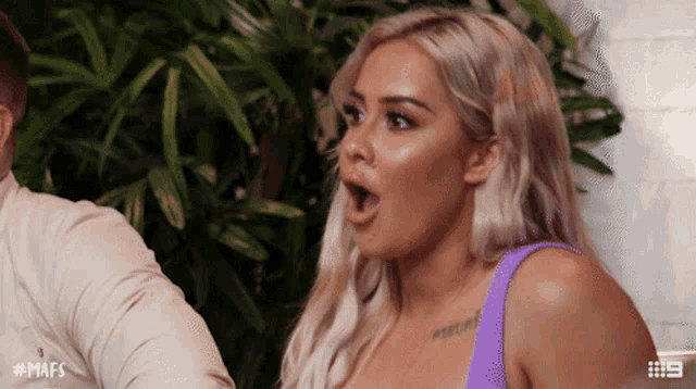 a woman with a surprised look on her face is wearing a purple tank top