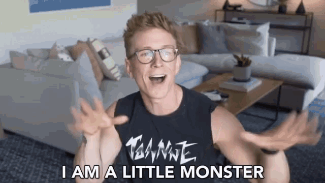 a man wearing glasses and a tank top that says " i am a little monster " on it