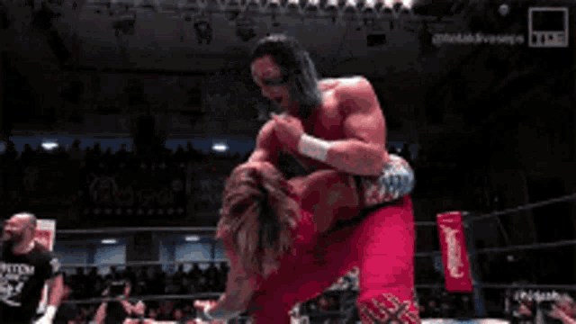 two men are fighting in a boxing ring with a referee in the background .