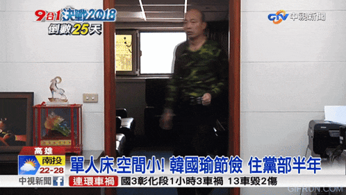 a man in a camouflage shirt is standing in a doorway on a television screen