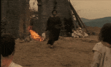a man is running towards a burning fire in a field