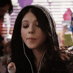 a woman wearing headphones and a hoodie looks down