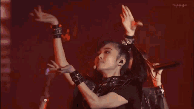 a group of women are dancing on a stage in front of a microphone in a dark room .