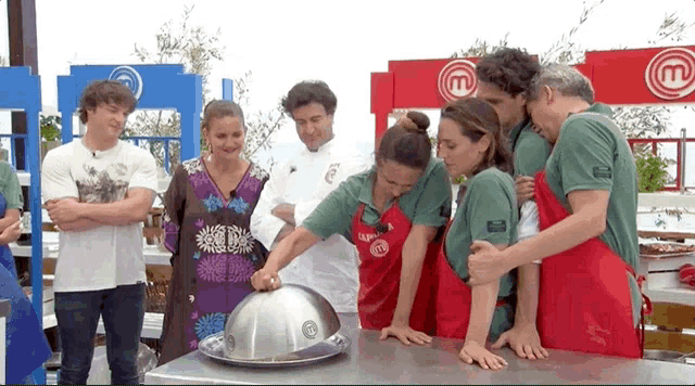 a group of people wearing aprons with the letter m on them are standing around a table