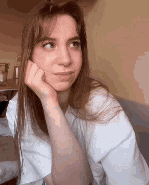 a woman with a hand on her chin looks to the side