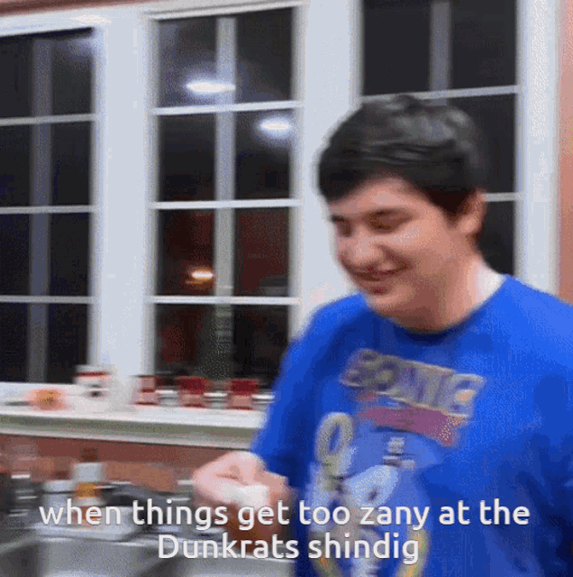 a man wearing a blue shirt that says sonic on it is smiling