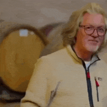 a man with long hair and glasses is standing in front of a bunch of barrels and says `` self-aware '' .