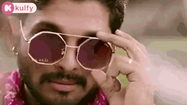 a man with a beard is wearing sunglasses and a scarf .