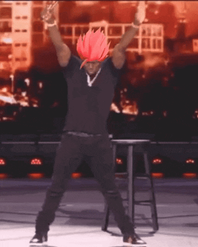 a man with red hair is dancing on a stage with his arms in the air .