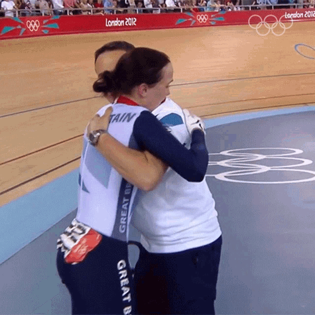 a woman in a great britain jersey hugging another woman on a track