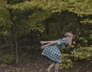 a woman in a plaid dress is standing in the woods