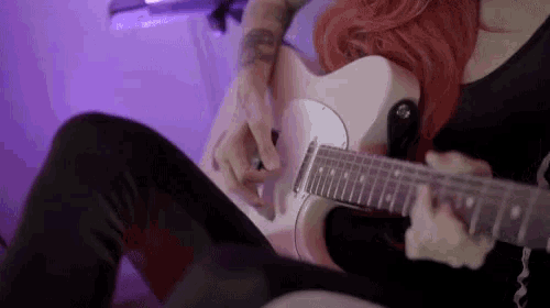 a woman with red hair playing a white guitar