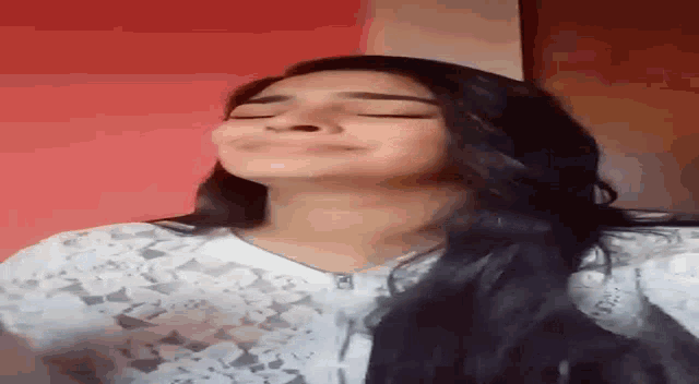 a woman with long black hair is smiling with her eyes closed