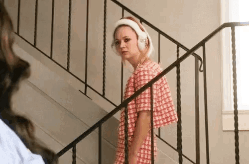 a woman wearing headphones is standing on the stairs .