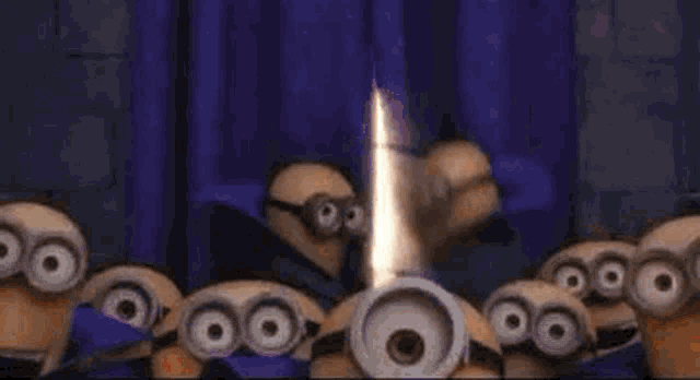 a group of minions are standing next to each other in front of a fire .