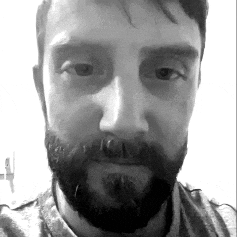 a man with a beard and mustache looks at the camera