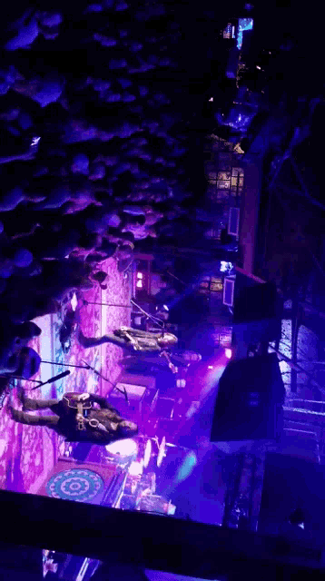 a group of people standing on a stage with purple lights behind them