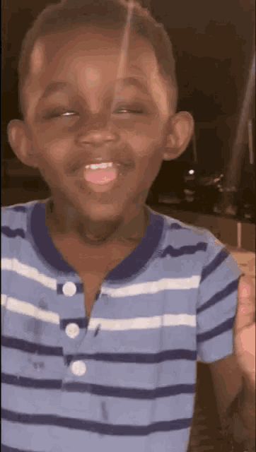 a young boy wearing a blue and white striped shirt with white buttons