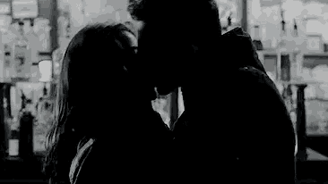a man and a woman are kissing in a bar .