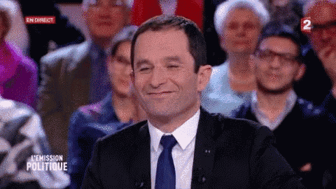 a man in a suit and tie is smiling in front of a crowd on a television show .