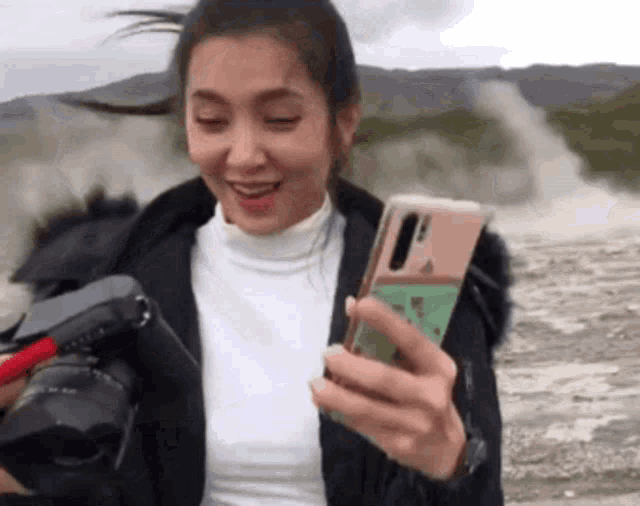 a woman is holding a camera and a cell phone in her hands .