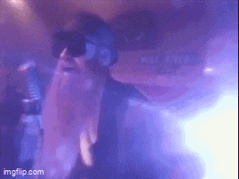 a person wearing sunglasses and a beard is dancing in a dark room .