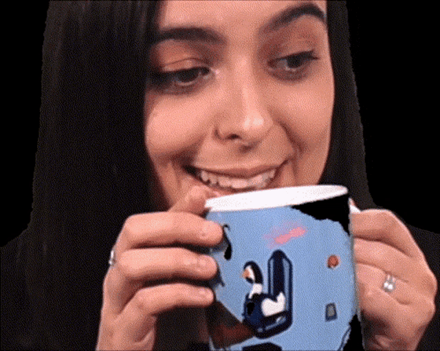 a woman is smiling while holding a cup with a penguin on it