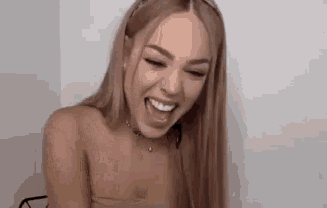a woman with long hair is laughing with her mouth open and wearing a headband .