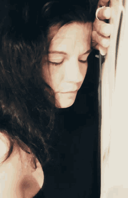 a woman with a ring on her finger looks down with her eyes closed
