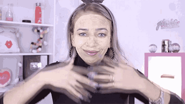 a woman is wearing a yellow mask on her face and making a heart with her hands .
