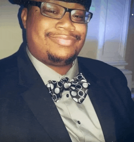a man wearing glasses and a bow tie is smiling for the camera