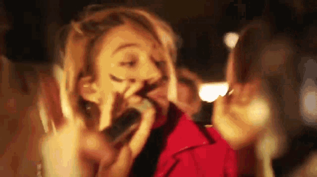 a woman in a red jacket is talking on a cell phone with her mouth open .