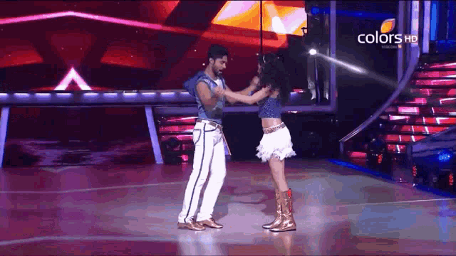 a man and a woman are dancing on a stage with the words colors hd in the background