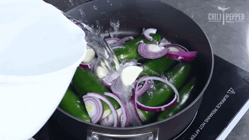 water is being poured into a pan of peppers onions and garlic with chili pepper written on the bottom