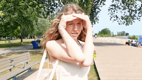 a woman covering her eyes with her hands in front of a beach
