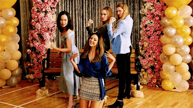 a group of women are posing for a picture in a room with balloons .