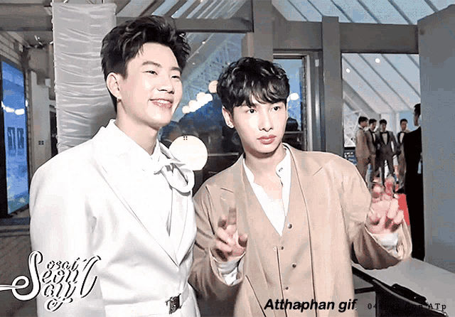 a couple of men standing next to each other with the words atthaphan gif on the bottom right