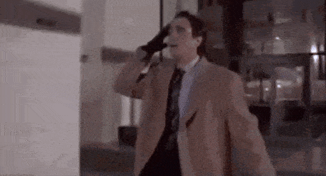 a man in a suit and tie is talking on a cell phone while walking down a street .