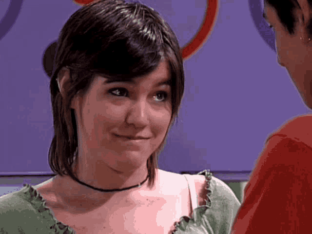 a girl in a green shirt is looking at a man in a red shirt