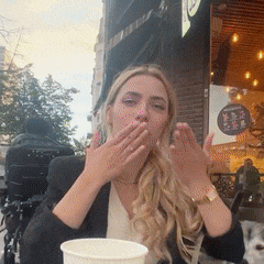 a woman covering her mouth with her hands while holding a cup