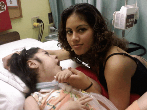 a girl laying in a hospital bed with an oxygen mask on her face