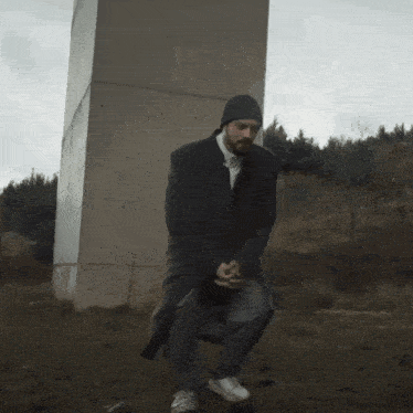 a man squatting down in front of a large concrete block