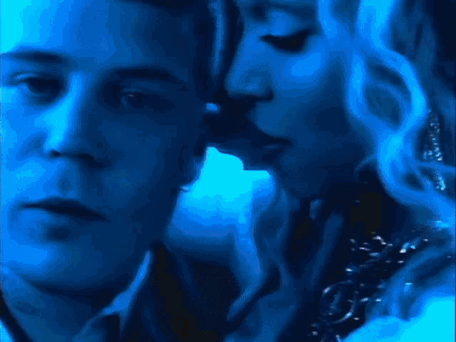 a woman is kissing a man on the cheek in a dark room